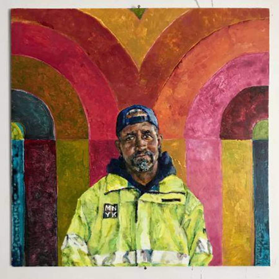 A portrait of a man in a bright yellow safety jacket stands against a colorful abstract background.