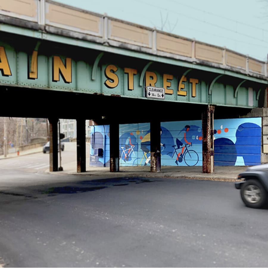 A vibrant mural depicting cyclists is showcased beneath a train overpass with "MAIN STREET" signage overhead.