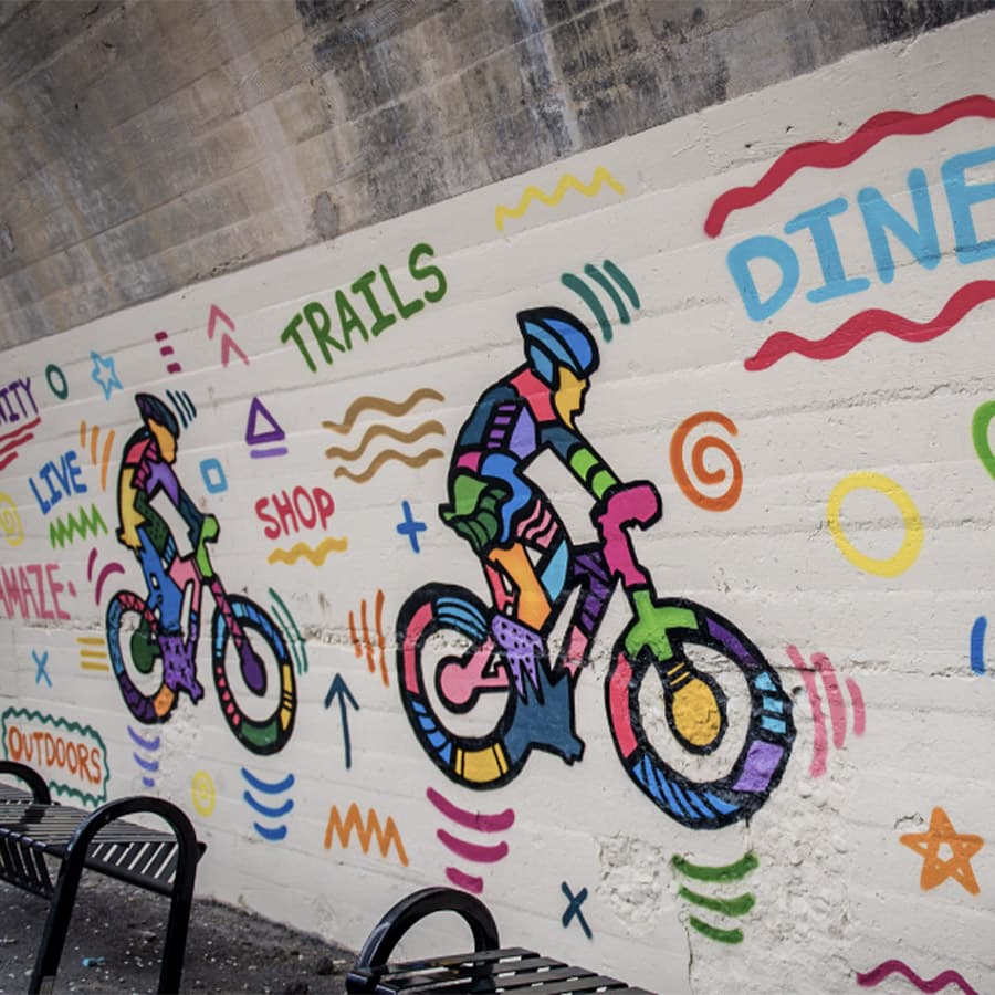 Colorful mural of two cyclists surrounded by vibrant text and shapes.