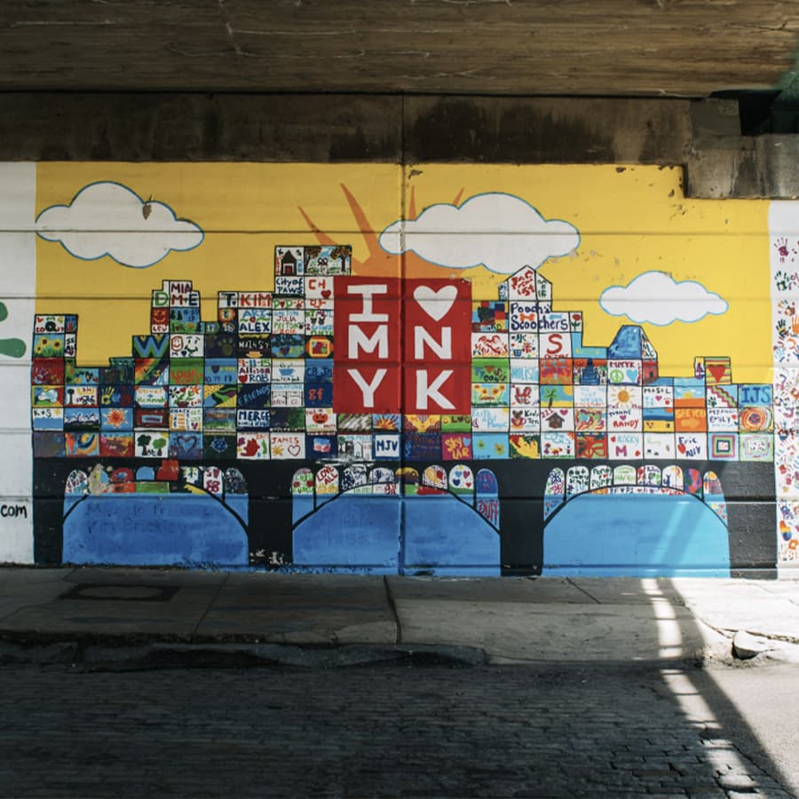Colorful mural with the text "I ❤️ MY INK" and various artistic symbols under a bridge.