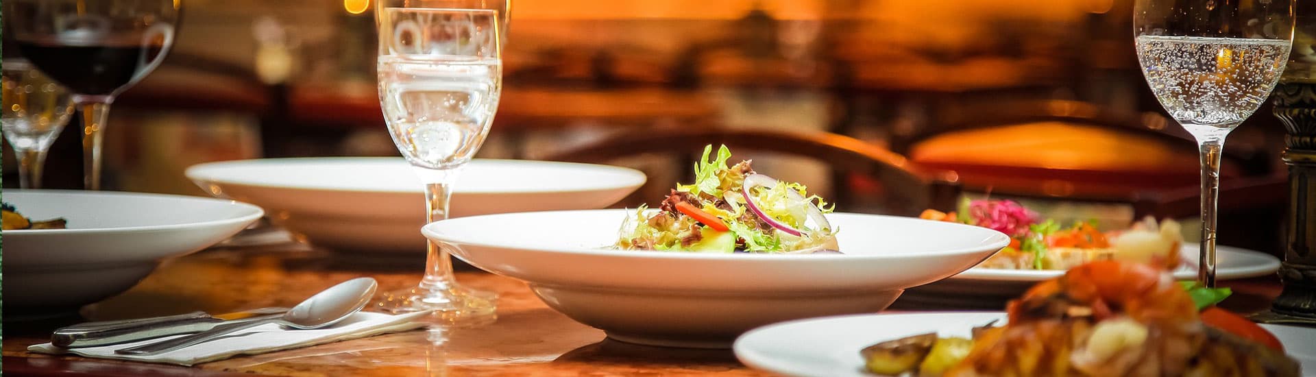 A beautifully set dining table featuring plates of gourmet food and elegant glassware.
