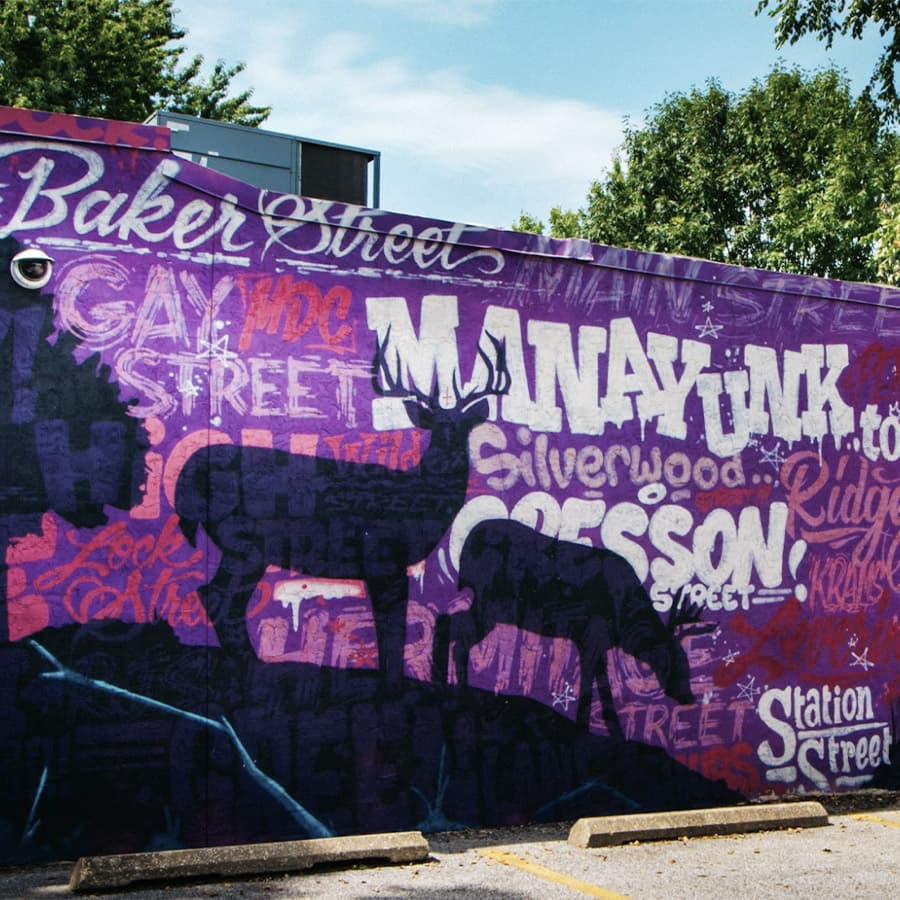 A vibrant purple mural featuring street names and silhouettes of deer.