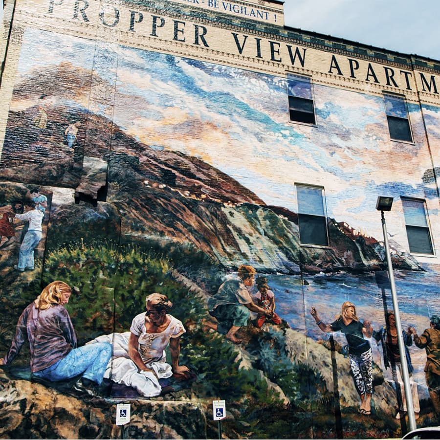 A vibrant mural depicting people interacting with nature on the side of a building.
