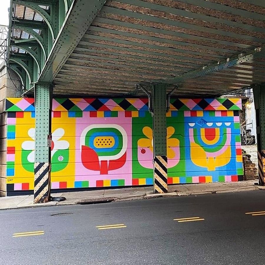 Colorful abstract mural under an elevated structure.