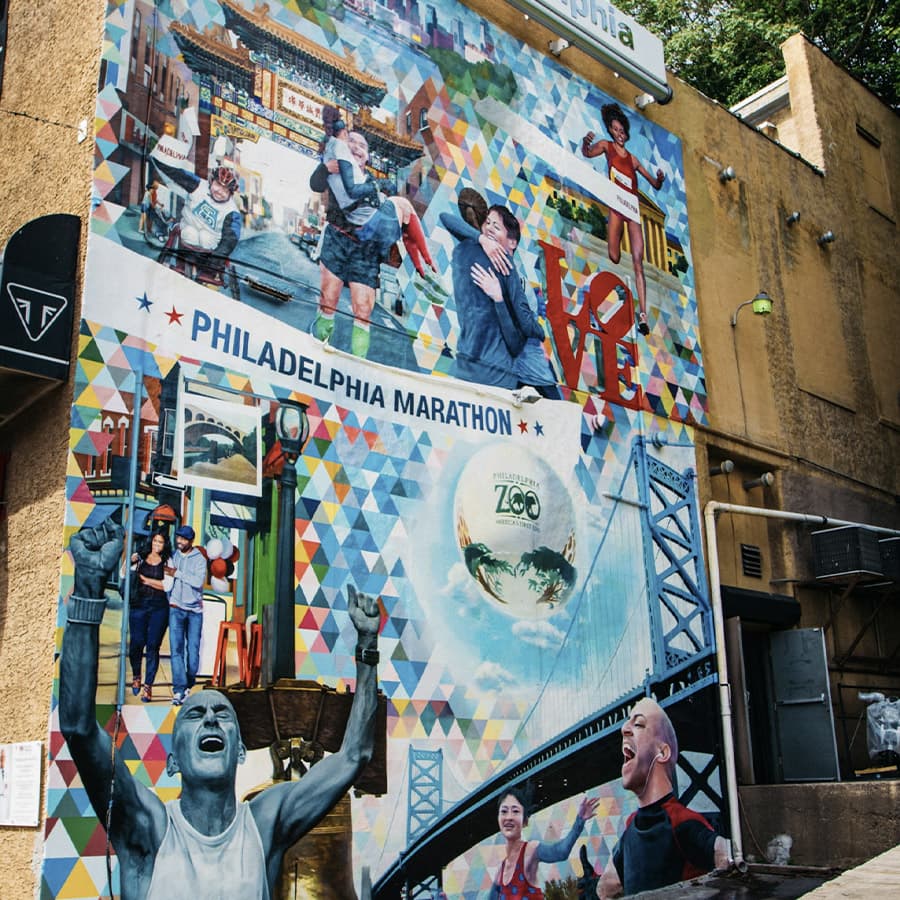 A vibrant mural celebrating the Philadelphia Marathon, featuring diverse runners and iconic city landmarks.